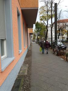 柏林费里恩沃农公寓的两个人沿着建筑旁边的人行道走