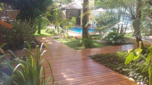 阿拉亚尔达茹达Casa da Arvore Apartamentos Pousada的庭院中的木道,带游泳池