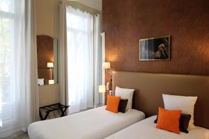 阿维尼翁里贾纳精品酒店的配有橙色枕头的酒店客房内的两张床