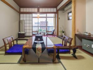 高知昭荣河滨日式旅馆的一间带桌椅和窗户的用餐室