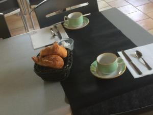 AlbaronLogis Hotel Restaurant Le Flamant Rose camargue的一张桌子,上面有两杯和一篮面包