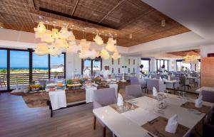 MecúfiMequfi Beach Resort的餐厅设有白色的桌子和白色的椅子及窗户。