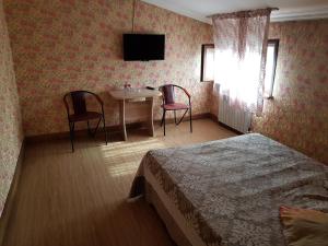 阿拉木图Mini Hotel Leila的酒店客房带一张床、一张桌子和椅子