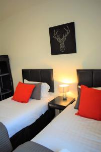 格兰奇茅斯Kelpies Serviced Apartments MacGregor- 2 Bedrooms的客房内的两张床和红色枕头
