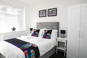 比林汉姆Belmont Apartments的白色卧室配有一张带彩色枕头的大床