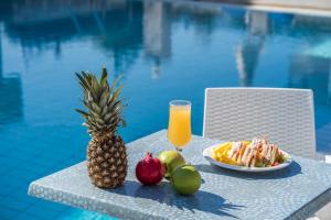 蒂锡利维Alamis Hotel & Apartments的 ⁇ 萝和水果放在泳池旁的桌子上