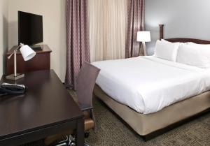 夏洛特Staybridge Suites - Charlotte Ballantyne, an IHG Hotel的酒店客房配有一张床、一张书桌、一张床和一张书桌。