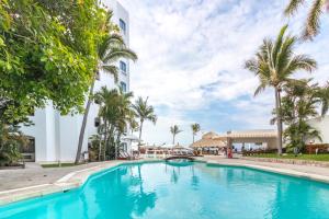 马萨特兰Gaviana Resort的棕榈树建筑前的游泳池