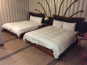 高雄巴中圣淘沙旅馆的酒店客房,配有两张带白色床单的床
