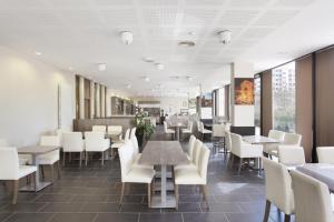 里昂里昂交汇奥达利斯城市公寓式酒店的用餐室配有桌子和白色椅子