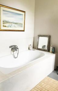 SimondiumKimi's Cottage的一个带镜子的房间内的白色浴缸