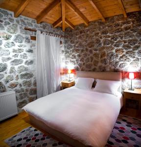 塞尼梅西奇卡罗勒凡达旅馆的卧室配有一张白色大床,位于石墙内
