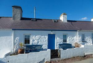 阿贝达隆Aberdaron Cottage 2 Bryn Chwilog的白色的房子,有蓝色的门和栅栏