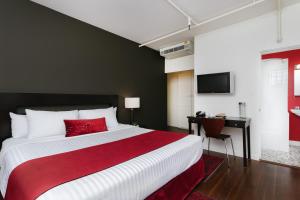温哥华莫达酒店的卧室配有红色和白色的床和书桌。