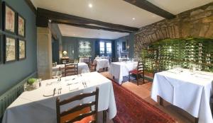 Austwick特拉多克乡村别墅的一间设有白色桌椅和石墙的餐厅