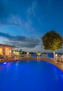斯卡拉绿洲海滩酒店的一个带椅子和树的蓝色大游泳池