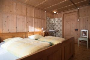 萨姆瑙恩Chasa Anguel的木墙客房内的一张大床