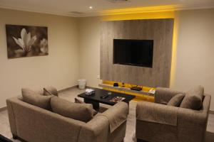 科威特莎米亚带露台家具的公寓的客厅配有2把椅子和平面电视