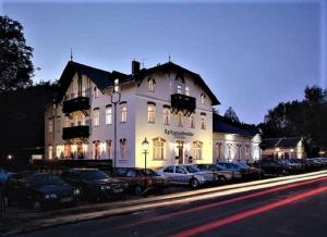 科斯维格赫斯特里切斯普兹格德穆酒店的一座白色的大建筑,前面有汽车停放