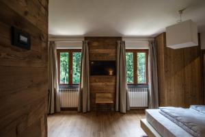 Roncobello奥洛比阿尔卑斯度假酒店的一间带木墙的卧室、两扇窗户和一张床