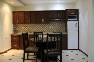 利雅德Dorar Darea Hotel Apartments- Al Malqa 2的厨房配有桌椅和冰箱。