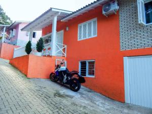 格拉玛多Glamour Gramado Residence的停在橘子屋前的摩托车