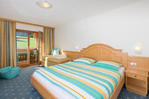 圣洛伦佐-迪塞巴托琳娜霍夫酒店的一间卧室配有一张大床和彩色条纹毯子