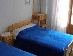 奥马斯帕纳吉亚斯Hotel Alexandros的一间卧室配有蓝色的床和镜子