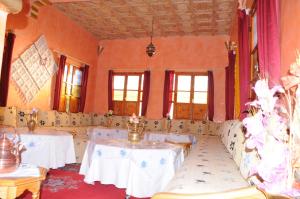 斯库拉Kasbah Elmehdaoui的配有白色桌椅和窗户的客房