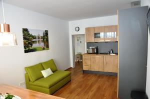 威斯巴登奎林公寓的一间带绿色椅子的客厅和一间厨房