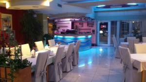 特罗吉尔Apartments Silvana的一间设有白色桌椅的餐厅和一间酒吧