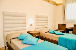 曼杜里亚BHB Hotel的客房配有两张带蓝色枕头的床。