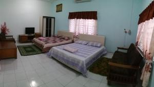 Paya Rewak达雅因迪娜民宿的一间带两张床的卧室和一台电视