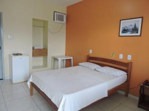 阿拉卡茹雷奥德索尔酒店的卧室配有白色的床和橙色的墙壁