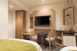 富士宫市富士宫富士急酒店 的酒店客房设有床、桌子和电视。