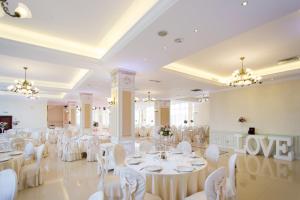 雅西国会大厦酒店的宴会厅配有白色的桌子和白色的椅子