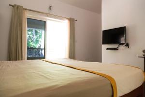 瓦加托Hill Top Goa Lodge的一间卧室设有一张大床和大窗户