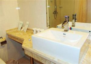 天津格林豪泰天津大寺梅江会展中心店的浴室设有白色水槽和镜子