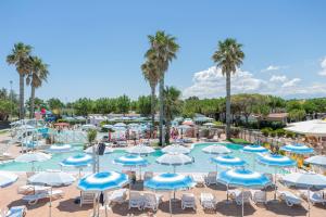 马帝斯兹罗Riva Nuova Camping Village的一个带蓝白遮阳伞和棕榈树的游泳池