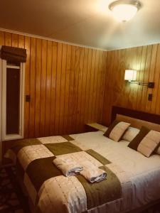 蓬塔阿雷纳斯Hotel Yellow Submarine的一间卧室配有一张带木墙的大床