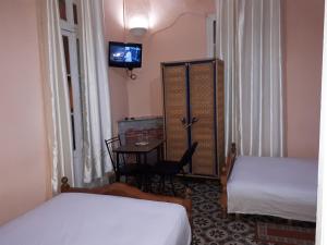 丹吉尔Pension Safari的客房设有两张床、一张桌子和电视。