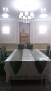 塞米伊Semey Hotel的一间带长桌和绿色椅子的用餐室