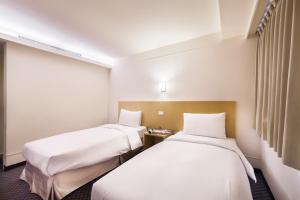 台北洛碁大饭店林森馆的配有白色床单的酒店客房内的两张床