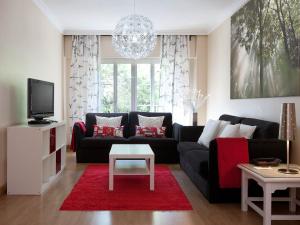 马德里TH阿拉瓦卡酒店的客厅配有黑色沙发和红色地毯。