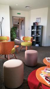 保拉扎克Ampaline HOTEL - Perigueux Boulazac的一间设有五颜六色的椅子和桌子的等候室