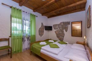 Veleniki丹妮拉住宿加早餐酒店的一间卧室配有一张带绿色窗帘的大床