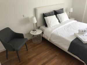 里斯本Luxury Apartment T2 - Saldanha的一间卧室配有一张大床和一把椅子