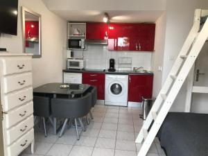 卢贝新城Residence Acapulco的一间小厨房,配有红色橱柜、一张桌子和一张书桌