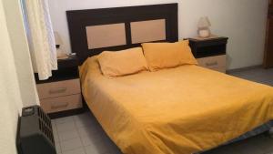 马德普拉塔德尔法鲁酒店的卧室配有一张带黄色床单和枕头的大床。