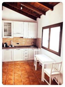 塞拉尔朱斯Appartamento Angela的厨房配有白色橱柜和桌椅